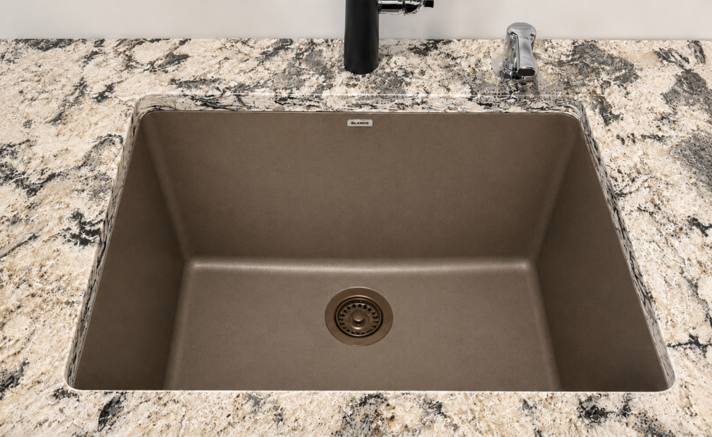 Brown single-basin sink set into a speckled granite countertop with a modern faucet above and a drain in the center.