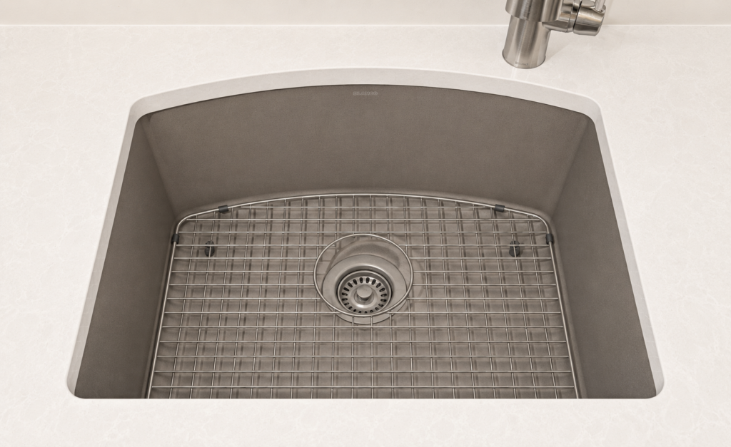 Top-down view of a beige-toned kitchen sink with a metal wire rack drainer over the drain and a faucet visible in the corner.